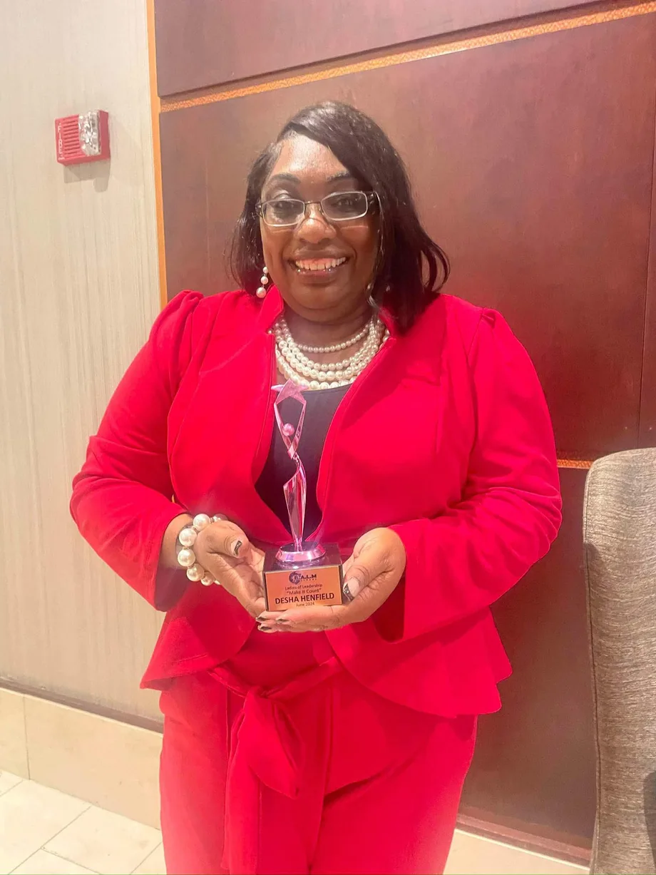 Desha holding a recognition award
